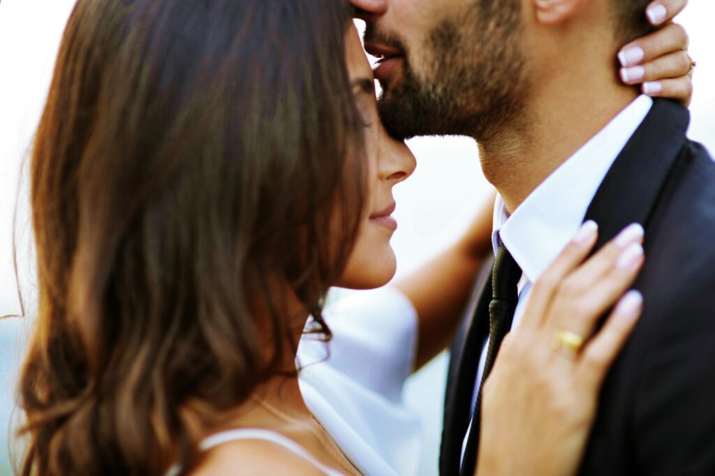 Groom kissing head of bride