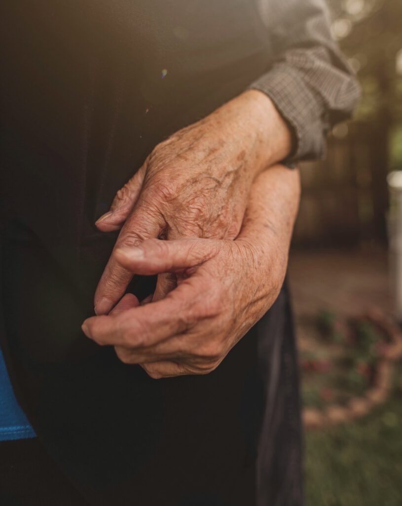 close up of old couple's hands while they hug, still best friends