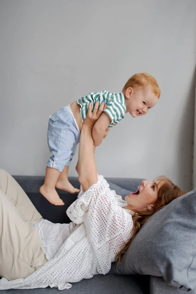 Mother lying on couch, holding up her kid smiling and teaching him good QI skills.